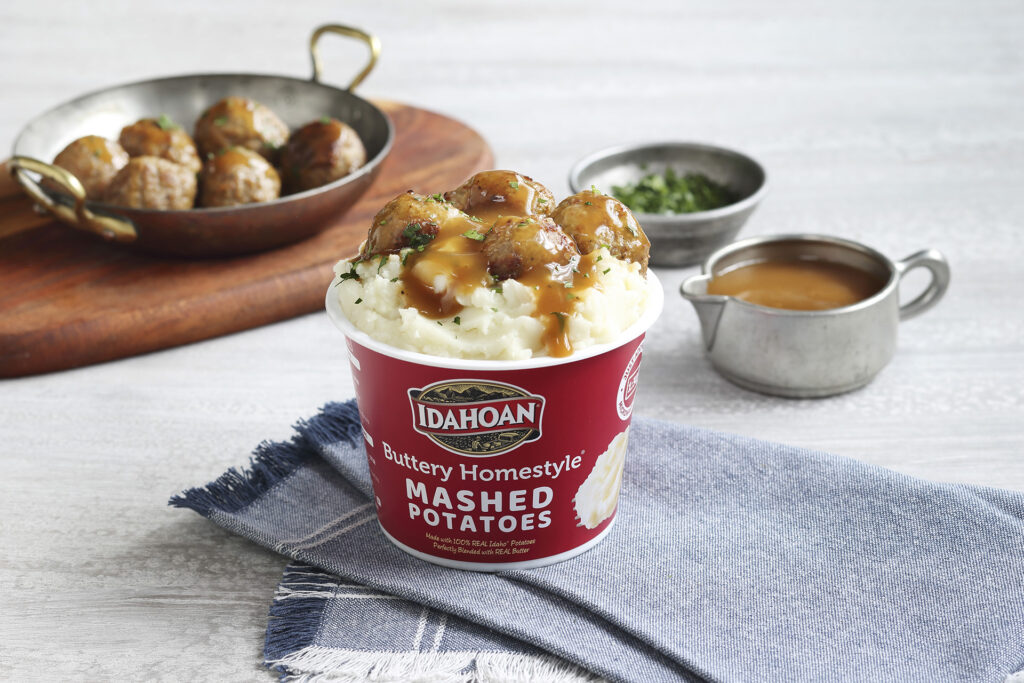 Idahoan Buttery Homestyle Mashed Potatoes in a cup with meatballs and gravy.